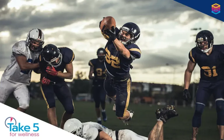 Time to tackle wellness tax barriers - American football player catching a football while leaping over an opponent - Benefits Alliance