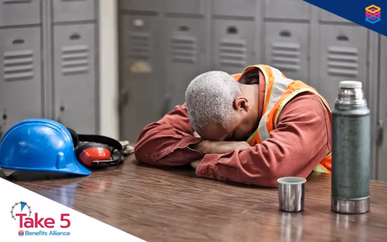 Employers play key role in the grief journey | Worker crying on a table with arms crossed over his face - Benefits Alliance